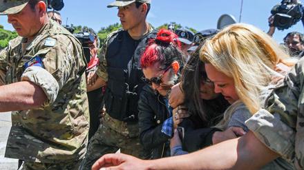 Ehefrauen der Besatzungsmitglieder trauern an der Küste. Sie werden von Soldaten eskortiert.