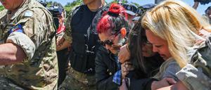 Ehefrauen der Besatzungsmitglieder trauern an der Küste. Sie werden von Soldaten eskortiert.