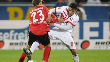 Julian Schuster (l) von Freiburg und Douglas Santos (r) von Hamburg kämpfen um den Ball.