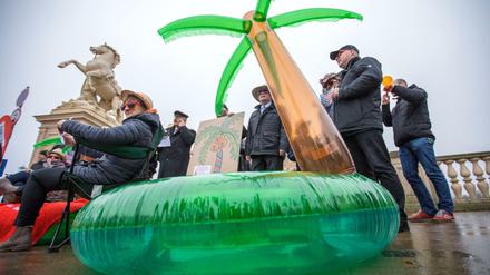 Politiker sitzen am 15.11.2017 bei einer Protestaktion gegen Steuerflucht vor dem Landtagsitz von Mecklenburg-Vorpommern. 