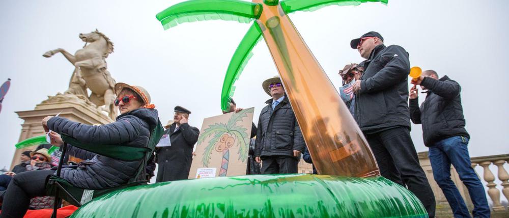 Politiker sitzen am 15.11.2017 bei einer Protestaktion gegen Steuerflucht vor dem Landtagsitz von Mecklenburg-Vorpommern.