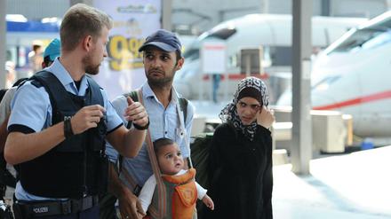Eine Familie aus Syrien mit einem Polizisten am Hauptbahnhof in München.
