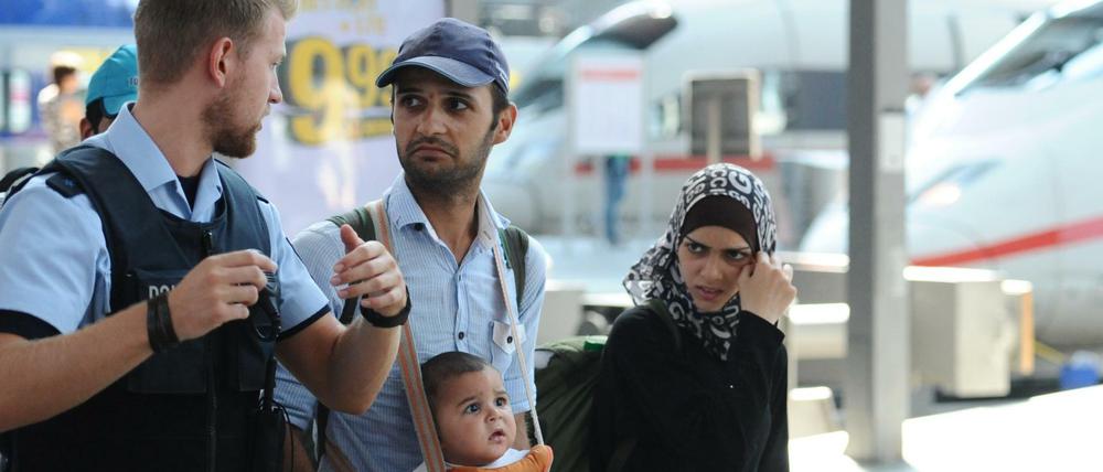 Eine Familie aus Syrien mit einem Polizisten am Hauptbahnhof in München.