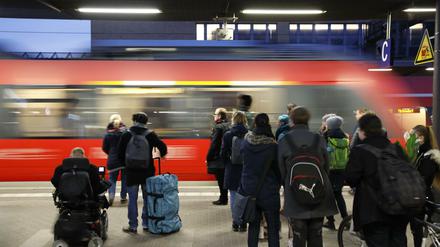 Menschen warten am Hauptbahnhof in Potsdam auf ihren Zug. 