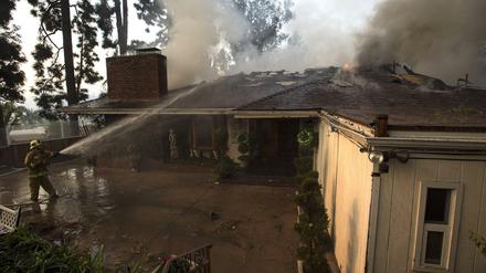 Kampf gegen die Flammen. Feuerwehrleute aus Los Angeles versuchen in Bel Air ein Haus vor dem Buschbrand zu retten.