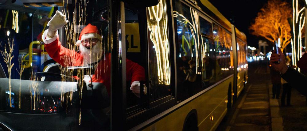 Ein als Weihnachtsmann verkleideter Busfahrer der Berliner Verkehrsbetriebe winkt in Berlin Passanten und Touristen von seinem Fahrerarbeitsplatz aus zu.
