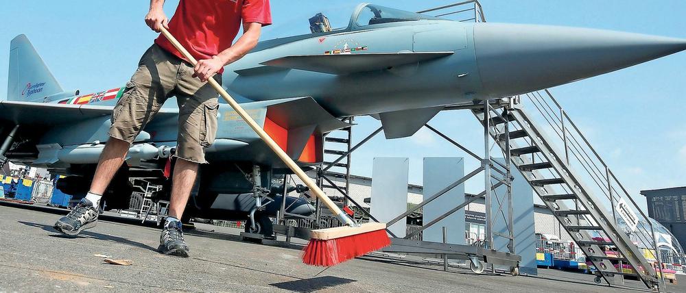 Ein Mann fegt auf der Internationalen Luft- und Raumfahrtausstellung (ILA) 2016 in Schönefeld, vor einem Eurofighter das Ausstellungsgelände.