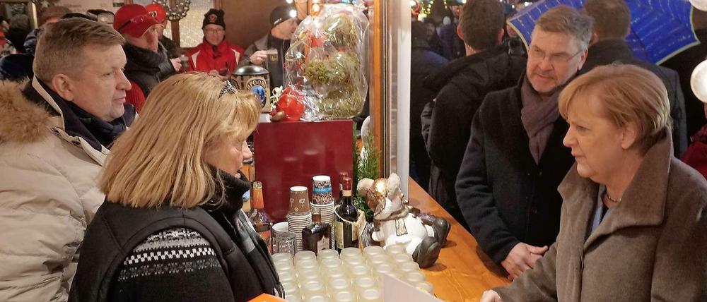 Bundeskanzlerin Angela Merkel und Michael Roden vom Schaustellerverband am Weihnachtsmarktstand der Familie Wollenschlaeger.
