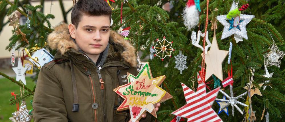 Timo zeigt Sterne aus verschiedenen Ländern am Weihnachtsbaum im heimischen Beeskow.