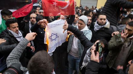 Teilnehmer einer Demonstration verbrennen am 10.12.2017 eine selbstgemalte Fahne mit einem Davidstern in Berlin im Stadtteil Neukölln. Die geplante Verlegung der US-Botschaft in Israel von Tel Aviv nach Jerusalem sorgte auch in Berlin für Proteste. Bei den pro-palästinensischen Demonstrationen wurden Fahnen mit dem Davidstern angezündet.