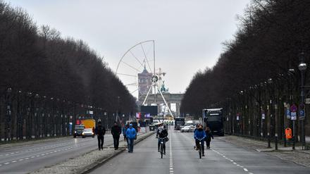 Passanten und Radfahrer sind am 29.12.2017 in Berlin auf der für den Verkehr gesperrten Straße des 17. Juni unterwegs, während im Hintergrund das Riesenrad für Deutschlands größte Silvesterparty aufgebaut wird.