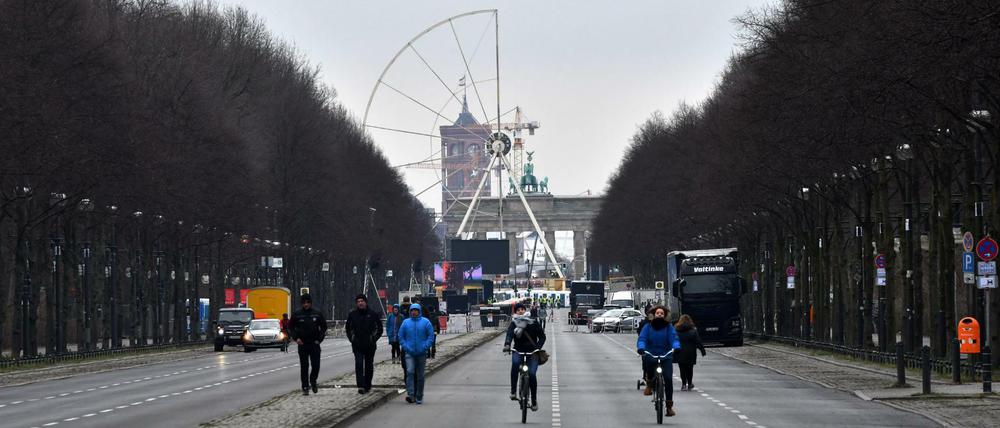 Passanten und Radfahrer sind am 29.12.2017 in Berlin auf der für den Verkehr gesperrten Straße des 17. Juni unterwegs, während im Hintergrund das Riesenrad für Deutschlands größte Silvesterparty aufgebaut wird.