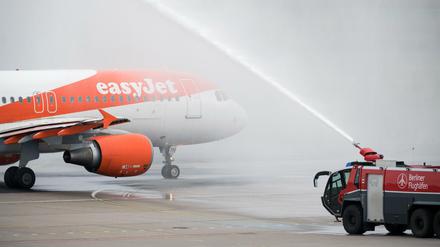 Ein Airbus der Fluggesellschaft Easyjet rollt in Berlin-Tegel vom Terminal C, wo Air Berlin früher Passagiere abfertigte, aus durch eine Wasserfontäne der Flughafenfeuerwehr zur Startbahn.
