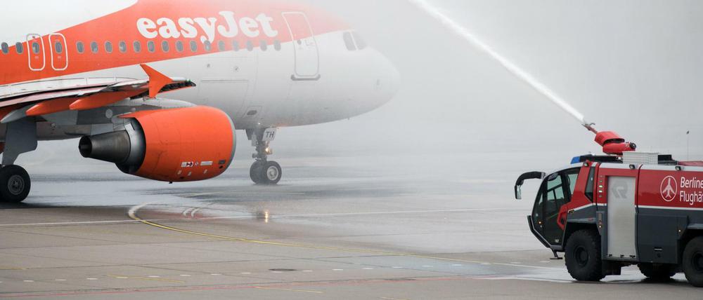 Ein Airbus der Fluggesellschaft Easyjet rollt in Berlin-Tegel vom Terminal C, wo Air Berlin früher Passagiere abfertigte, aus durch eine Wasserfontäne der Flughafenfeuerwehr zur Startbahn.