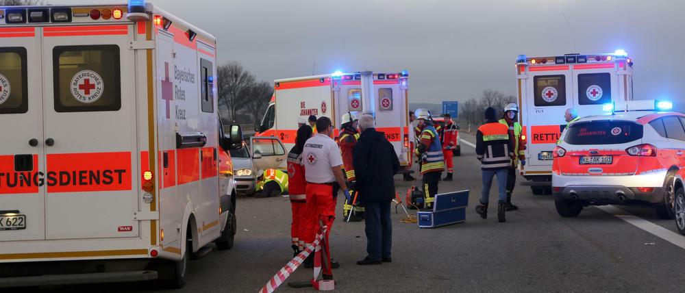 Sanitäter und Feuerwehrleute stehen zwischen mehreren Krankenwagen auf der Autobahn. 