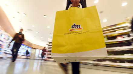 Eine Kundin der Drogeriemarktkette dm geht mit einer dm-Tasche durch eine Filiale.