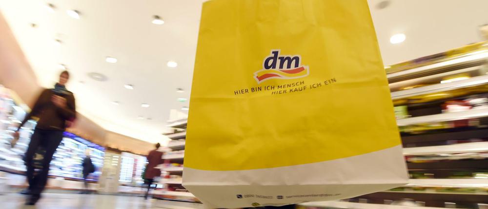 Eine Kundin der Drogeriemarktkette dm geht mit einer dm-Tasche durch eine Filiale.