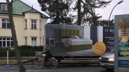 Überbreiter Werbeanhänger, der am Roseneck in einer von der Firma selbst beim Ordnungsamt beantragten Ladezone dauergeparkt wurde, samt Gefahr für Radfahrer.