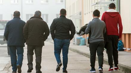 Asylbewerber gehen über das Gelände der Zentralen Ausländerbehörde (ZABH) in Eisenhüttenstadt (Brandenburg). 