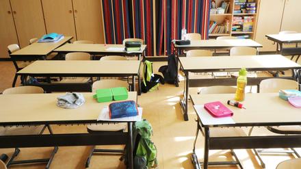 Schulutensilien liegen auf Schultischen in einer Grundschule.