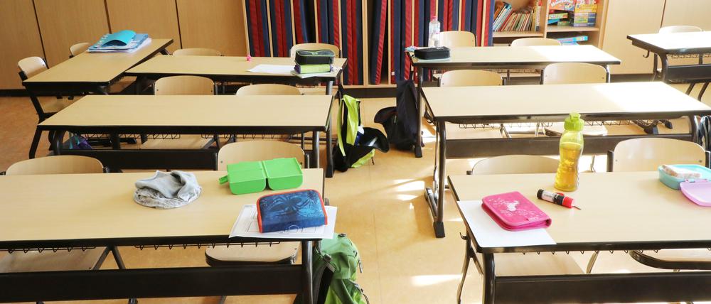 Schulutensilien liegen auf Schultischen in einer Grundschule.