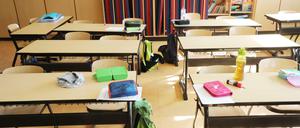 Schulutensilien liegen auf Schultischen in einer Grundschule.