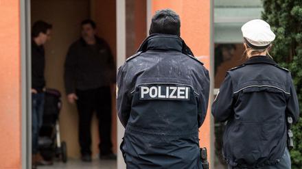 Zwei Polizisten stehen vor dem Mehrfamilienhaus, in dem die Polizei in der Nacht zum Montag einen mit Messern bewaffneten Familienvater erschossen hat. 