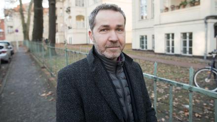 Pankows Bezirksbürgermeister Sören Benn (Die Linke) steht auf einem Gehweg, links parkende Autos, rechts Fahrradständer.