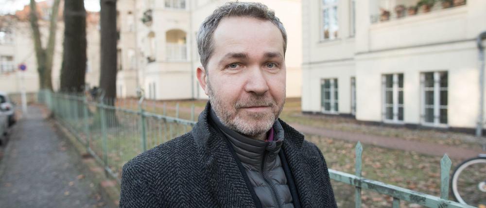 Pankows Bezirksbürgermeister Sören Benn (Die Linke) steht auf einem Gehweg, links parkende Autos, rechts Fahrradständer.