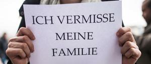 Ein Mitglied des Flüchtlingsrats Berlin hält ein Schild in den Händen.