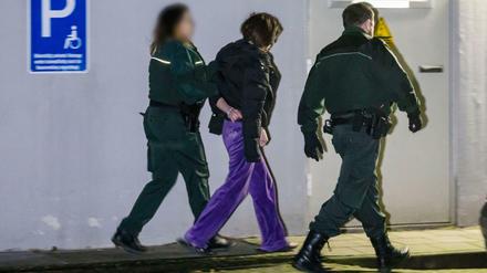 Beamte des Zolls führen eine festgenommene Person bei einer Razzia gegen Schwarzarbeit ab. 