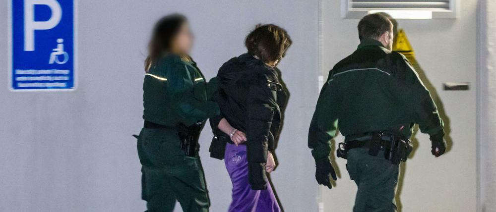 Beamte des Zolls führen eine festgenommene Person bei einer Razzia gegen Schwarzarbeit ab.