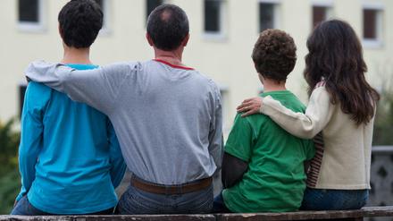 Vereint - ein Vater aus Syrien sitzt mit seinen drei Kindern vor einem Asylwohnheim. 