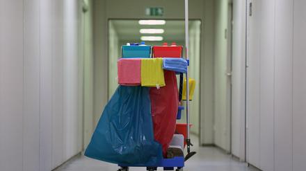 Ein Wagen mit Reinigungsmittel und Müllsäcken steht in einem Büroflur.
