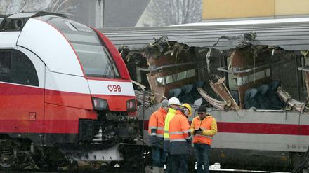 Mitarbeiter der Österreichischen Bundesbahnen (ÖBB) stehen vor den zwei durch eine Kollision beschädigten Zügen. 