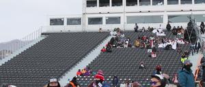 Gewohntes Bild. Nur wenige Zuschauer sitzen bei windigem Wetter auf der Tribüne