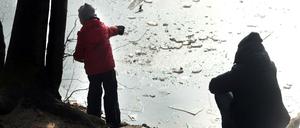 Winter in Berlin. Die Seen frieren langsam zu, sind aber noch nicht sicher. Am Schlachtensee Vater und Sohn werfen Eis auf die Eisfläche. 