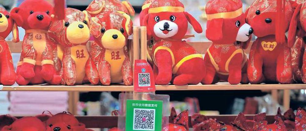 Im Jahr des Hundes. Ladenregal mit vierbeinigen Maskottchen. Die Schilder mit den QR-Codes gehören zu den allgegenwärtigen Bezahlverfahren Alipay (oben) und WeChat, dem chinesischen Pendant von WhatsApp. 