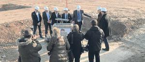 Männer, die auf Steine schauen: Noch steht auf dem Gelände des künftigen Warenverteilzentrums in Wustermark außer dem Stein nichts. Aber das soll sich schnell ändern. In zwei Jahren soll die Brache bebaut sein. 