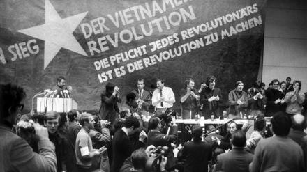 Etwa 3000 Personen, meist Studenten, nehmen an der vom Sozialistischen Deutschen Studentenbund (SDS) durchgeführten "Internationalen Vietnam-Konferenz" in der TU teil. Auf dem Bild vor einer übergroßen Vietkong-Fahne am Tisch stehend sind zu sehen - von links: K.D. Wolff (am Rednerpult), Dr. Klaus Meschkat, Dr. Johannes Agnoli, Christian Semmler, Gaston Salvatore, Rudi Dutschke, Günther Ament, Kurt Steinhaus und Tariq Ali.