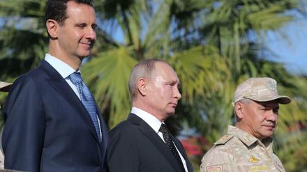 Russland und Iran halten das Regime von Präsident Assad (l.) an der Macht. (Das Foto zeigt den russischen Präsidenten Putin, Assad und den russischen Verteidigungsminister Schoigu bei einer Militärparade auf der russischen Luftwaffenstützpunkt in Hmeimin in Syrien am 11. Dezember 2017). 