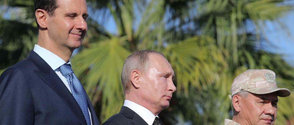 Russland und Iran halten das Regime von Präsident Assad (l.) an der Macht. (Das Foto zeigt den russischen Präsidenten Putin, Assad und den russischen Verteidigungsminister Schoigu bei einer Militärparade auf der russischen Luftwaffenstützpunkt in Hmeimin in Syrien am 11. Dezember 2017).