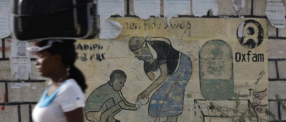 Eine Frau läuft in Haiti an einer Oxfam-Tafel vorbei.