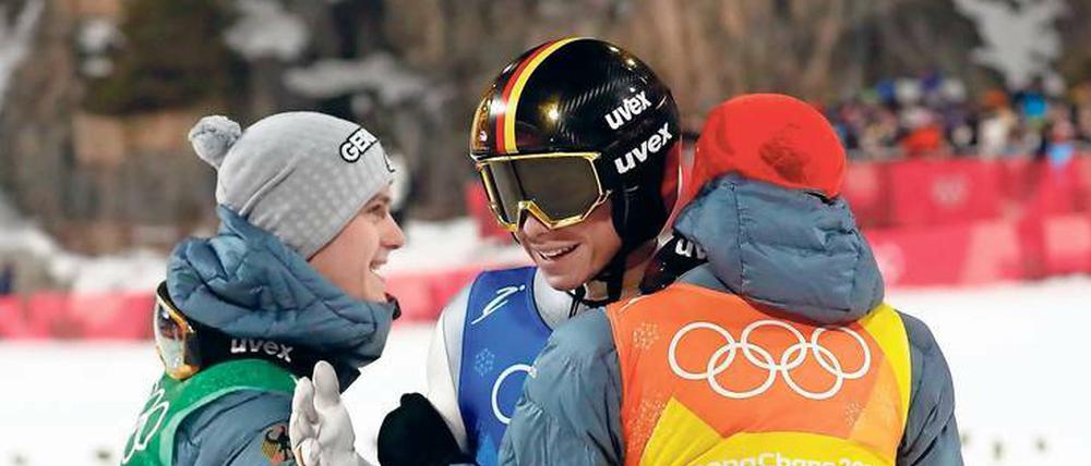 Andreas Wellinger wird von seinen Teamkollegen Stephan Leyhe and Richard Freitag beglückwünscht.