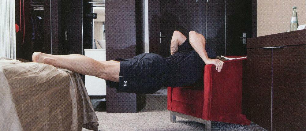 Man muss ja nicht immer alles gleich machen. Ein Mann zwischen Stuhl und Bett. Aus der Fotoreihe "TABLE ROWING" von Peter Piller.
