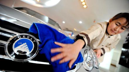 Ein Frau putzt die Frontpartie eines Autos der Marke Geely im Hauptquartier des chinesischen Autokonzerns Hangzhou.