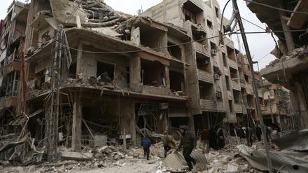 Syrer inspizieren Straßen und Gebäude, die durch Angriffe der syrischen Luftwaffe auf Ost-Ghouta zerstört wurden.