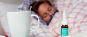 Medikamente und ein Fiberthermometer liegen auf einem Nachttisch.