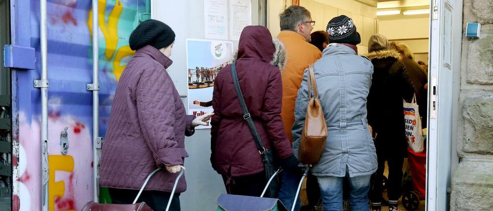 Kunden der Essener Tafel gehen mit ihren Einkaufstrolleys zur Ausgabestelle.