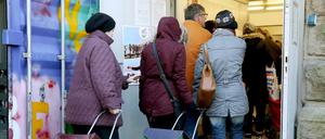 Kunden der Essener Tafel gehen mit ihren Einkaufstrolleys zur Ausgabestelle. 